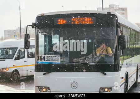 Moskau, Russland - 2. MAI 2018: Ein Stadtbusfahrer sitzt und nutzt das Telefon an einer Haltestelle wartet auf Passagiere. Draußen regnet es Stockfoto