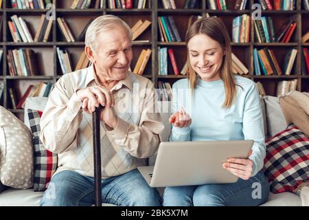 Vater und Tochter zu Hause Bibliothek sitzen Blick auf Laptop lächelnd Stockfoto