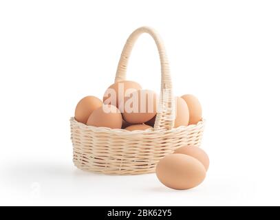 Eier im Weidenkorb auf den weißen Hintergründen mit Schnittwegen isoliert Stockfoto