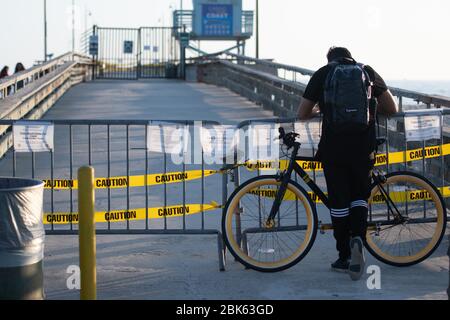 Los Angeles, USA. Mai 2020. Ein Mann steht mit seinem Fahrrad an der geschlossenen Anlegestelle von Venice Beach. Die Strände VON LA County sind aufgrund der Krise in Corona offiziell geschlossen. Bild: Maximilian Haupt/dpa/Alamy Live News Stockfoto