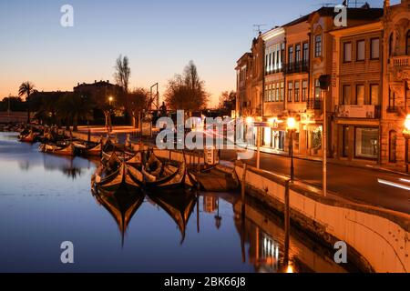 Aveiro, Portugal - April 2019: Traditionelle Moliceiro Boote dockten nach Sonnenuntergang im Hauptkanal bei Rossio an. Stockfoto