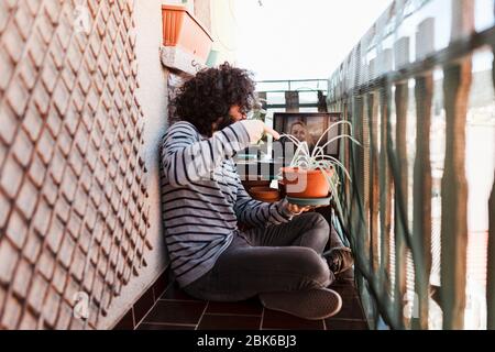Junger Afro Kaukasier mit Laptop auf seinem Balkon in Videocall Stockfoto