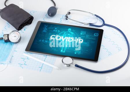 Tablett-pc und Arztwerkzeuge mit COVID-19-Beschriftung, Coronavirus-Konzept Stockfoto