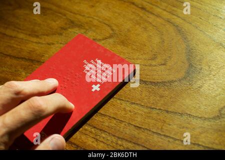 Männliche Hand, die einen Schweizer Pass auf einen Holztisch legt Stockfoto