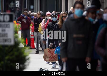 Peking, April 14. Mai 2020. Während der Coronavirus-Pandemie im New Yorker Stadtteil Brooklyn, USA, am 14. April 2020, warten Menschen mit Gesichtsmasken in der Schlange, um in einem Geschäft einzukaufen. ZU XINHUA SCHLAGZEILEN VOM 2. MAI 2020. Kredit: Michael Nagle/Xinhua/Alamy Live News Stockfoto