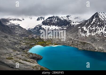 Luftaufnahme von Türkis Ala-Kul See im Tien Shan Gebirge mit weißen Nebel Wolken in Karakol Nationalpark, Kirgisistan Stockfoto