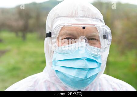 Porträt des älteren Mannes trägt Hasmat Anzug, Maske und Handschuhe im Freien - covid-19 Pandemie Stockfoto