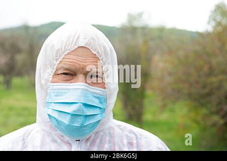 Porträt des älteren Mannes trägt Hasmat Anzug, Maske und Handschuhe im Freien - covid-19 Pandemie Stockfoto
