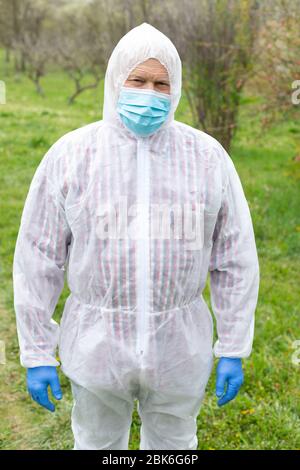Porträt des älteren Mannes trägt Hasmat Anzug, Maske und Handschuhe im Freien - covid-19 Pandemie Stockfoto