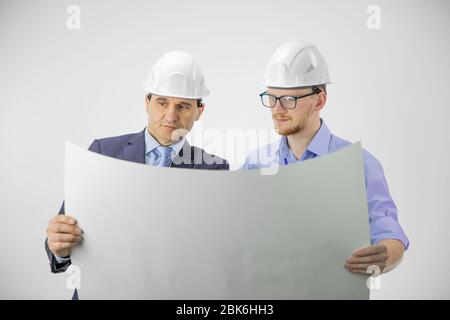 Zwei Ingenieure in Hüten diskutieren Blaupause isoliert auf weißem Hintergrund Stockfoto