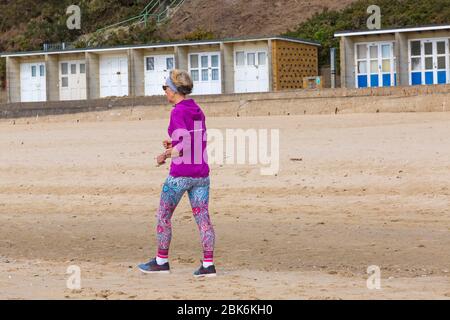 Poole, Dorset, Großbritannien. Mai 2020. UK Wetter: Sonnige Zauber an den Stränden von Poole an der Südküste, wenn die Menschen ihre erlaubte Übung machen, die meisten halten sich an die Coronavirus Richtlinien. Die Strände sind praktisch verlassen, abgesehen von den Trainierenden. Frau, die am Meer entlang geht. Quelle: Carolyn Jenkins/Alamy Live News Stockfoto