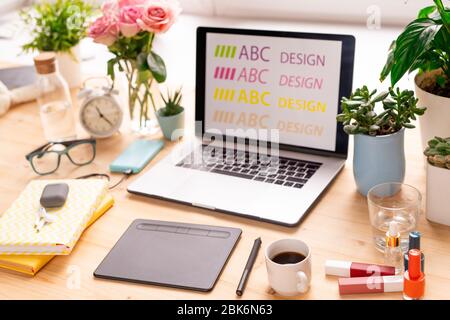 Laptop, Pad, Bücher, Make-up-Produkte, Kaffee, häusliche Pflanzen und andere Dinge auf dem Arbeitsplatz der zeitgenössischen kreativen weiblichen Designerin Stockfoto