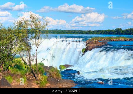 Iguazu Wasserfälle in Argentinien, Blick von Teufelsmund an einem sonnigen Tag, blauer Himmel mit Wolken. Nahaufnahme auf dem oberen Teil des Wasserdampfes über dem Iguazu Rive Stockfoto