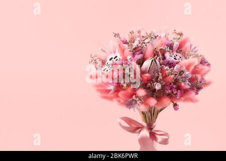 Schönes Bouquet von rosa getrockneten Blumen auf einem rosa Hintergrund, close-up. Stockfoto