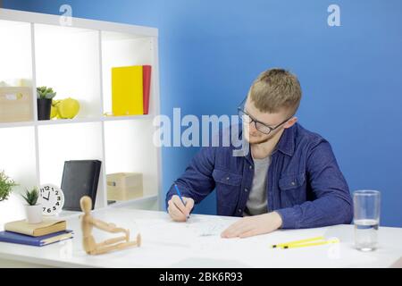 Kreative Modedesignerin arbeitet an Skizzen, zeichnet mit Bleistift in blauen Arbeitsbereich Stockfoto