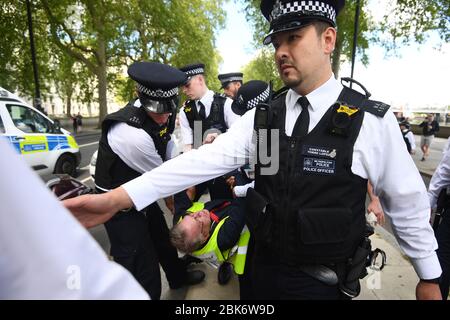 Ein Mann wird von Polizisten bei einem Protest gegen die Blockade von Covid-19 vor dem New Scotland Yard in London mitgenommen. Stockfoto