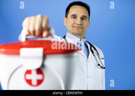 Schöner dunkler Haar 40s männlichen Arzt hält rotes Kreuz medizinische Hilfe-Kit Stockfoto