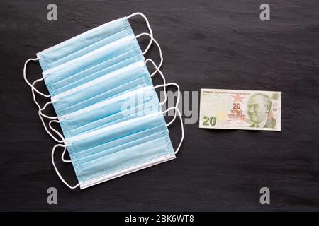 Gesichtsmaske und türkische Lira-Banknoten auf schwarzem Hintergrund. Teure Gebühren für medizinische Masken wegen der Coronavirus-Pandemie in der Türkei. Konzept von mir Stockfoto