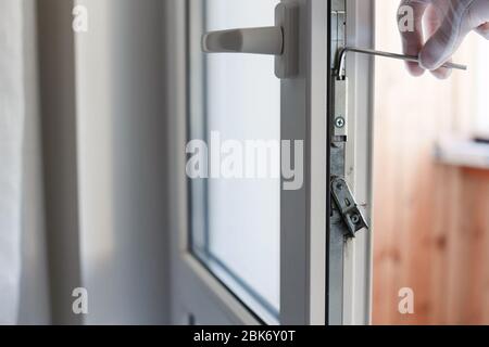 Man's Hand macht die Einstellung der Hardware der uPVC Türmechanismus mit einem Inbusschlüssel Stockfoto