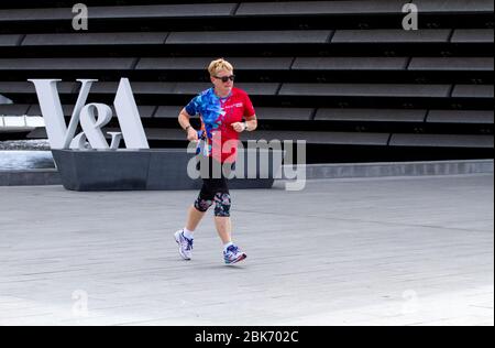 Dundee, Tayside, Schottland, Großbritannien. Mai 2020. UK Wetter: Heute Morgen ist es ziemlich bewölkt mit ein paar Sonneneinflüssen in Dundee, Temperaturen bis 15 Grad Eine ältere Joggingjoggerin, die während der Sperrbeschränkungen von Covid-19 in ganz Schottland am V&A Design Museum entlang der Küste entlang joggt. Quelle: Dundee Photographics/Alamy Live News Stockfoto