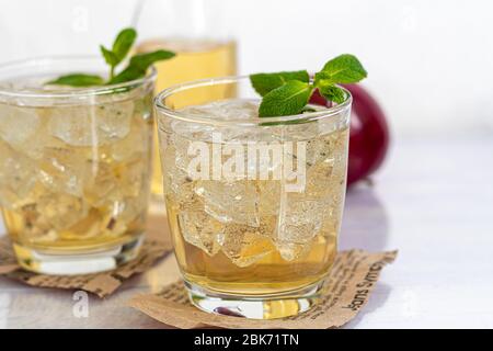 Gesunde Bio-Lebensmittel. Apfelmost in einer Glasschale und frische rote Äpfel auf hellem Hintergrund. In einem Glas Eiswürfel und in der Nähe Zimtstangen. Cop Stockfoto