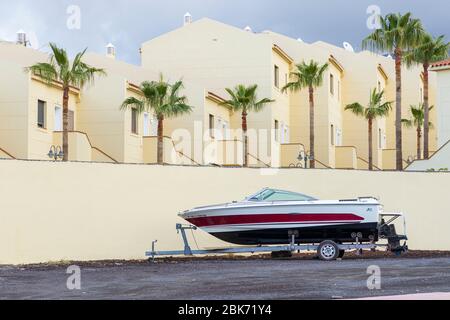 Schnellboot auf einem Anhänger, der während der Blockade des Covid 19 neben einer Apartmentanlage im touristischen Ferienort Costa Adeje, Teneriffa, Kanarische Inseln, geparkt wurde Stockfoto