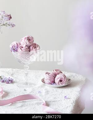 Violett süß hausgemachte Zephyr oder Marshmallow aus schwarzer Johannisbeere um lila Blüten auf weißem Tischtuch und hellen Hintergrund Stockfoto