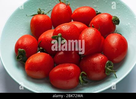 Schüssel mit frisch gewaschenen frischen Tomaten mit Wassertröpfchen in der Nähe in einem Konzept einer gesunden Ernährung Stockfoto