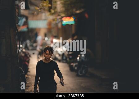 Hanoi, Vietnam: 18. Oktober 2019: Eine eineinreisende Asiatin geht in einer Seitenstraße zur Kamera, rechts ist Platz für Text Stockfoto