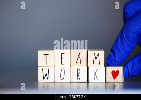 Holzwürfel mit den Worten Team Work für Business Concept oder Health Care Krankenschwestern oder Arzt Covid-19, Coronavirus, in Teams weltweit arbeiten Stockfoto