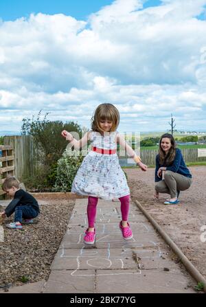 Camptoun, East Lothian, Schottland, Vereinigtes Königreich. Mai 2020. Eine Gemeinde im Lockdown: Bewohner einer kleinen ländlichen Gemeinde zeigen, wie das Leben im Lockdown für sie ist. Im Bild: Alice, 5 Jahre alt, spielt gerne hopscotch Stockfoto