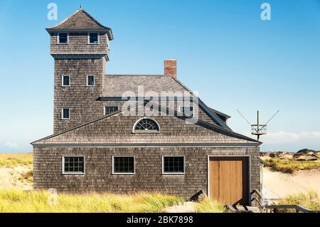 Der Turm und das Äußere der alten Hafen Lebensrettungsstation erhebt sich über den Gras bedeckten Dünen an der nationalen Küste am Rennpunkt in Provinceto Stockfoto