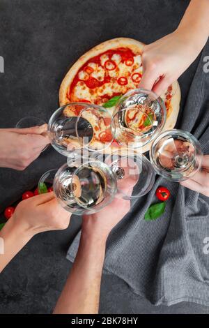 Hände zusammen mit Gläsern Weißwein auf der Pizza im Hintergrund Stockfoto