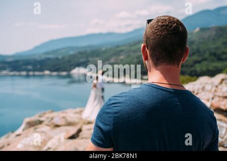 Mann, der auf das Meer schaut und von hinten auf den Berg sphotographed Stockfoto