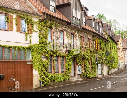 Kleines Hotel an der Straße. Die Hotelwand ist mit Efeu bedeckt. Schild auf dem Gebäude. Hotel in Bayern. Pauschalreisen nach Deutschland. Ein schönes Hotel. Stockfoto