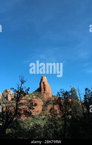 Atemberaubende Felsformationen aus rotem Sandstein und weißem Kalkstein mit Baumsilhouetten im Vordergrund auf dem Brins Mesa Trail in Sedona, Arizona, USA Stockfoto