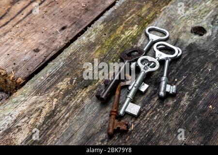 Alte Schlüssel in verschiedenen Größen auf rustikalen verwitterten Holzplanken Stockfoto