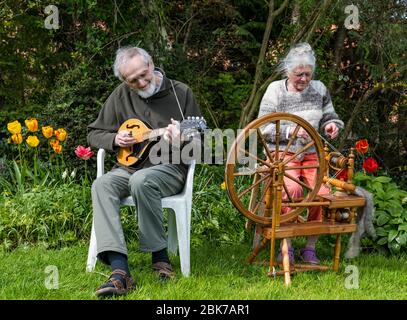 Camptoun, East Lothian, Schottland, Vereinigtes Königreich. Mai 2020. Eine Gemeinde im Lockdown: Bewohner einer kleinen ländlichen Gemeinde zeigen, wie das Leben im Lockdown für sie ist. Im Bild: Alan und Jancis. Alan feierte seinen 80. Geburtstag im Lockdown. Er spielt die Mandoline und verpasst seine üblichen Gigs und wöchentlichen Übungssitzungen mit Mitmusikern in der Band The Tone Poets. Jancis spinnt Wolle von Shetland Schafen, die von einem Nachbarn bewirtschaftet werden Stockfoto