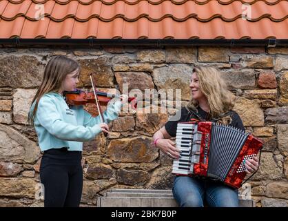 Camptoun, East Lothian, Schottland, Vereinigtes Königreich. Mai 2020. Eine Gemeinde im Lockdown: Bewohner einer kleinen ländlichen Gemeinde zeigen, wie das Leben im Lockdown für sie ist. Im Bild: AVA, 10 Jahre alt, und ihre Mutter, Harley, eine Musikerin, spielen die Geige und Akkordeon in der Melodie "Somewhere Over The Rainbow" Stockfoto