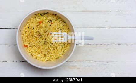 instant Nudeln mit Kunststoff Gabel auf weißen Holztisch oben Ansicht Nahaufnahme mit Kopierraum Stockfoto