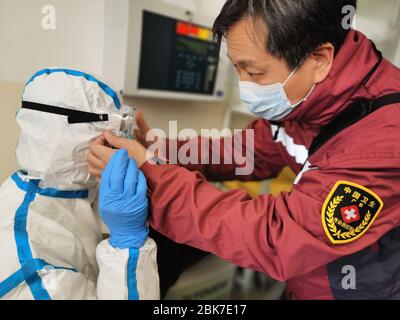 (200502) -- PEKING, 2. Mai 2020 (Xinhua) -- Peng Zhiqiang, Leiter des chinesischen medizinischen Teams in Serbien, hilft einem Teammitglied, in einem Krankenhaus für COVID-19-Patienten in Belgrad, Serbien, Schutzkleidung zu tragen, 25. März 2020. Viele Menschen haben sich an ihren Posten festgeklebt, während die Welt gegen die COVID-19-Epidemie kämpft. (Chinesisches medizinisches Expertenteam nach Serbien/Handout über Xinhua) Stockfoto