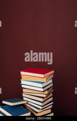 Viele Stapel von Lehrbüchern für Hochschulprüfungen in der Bibliothek auf einem braunen Hintergrund Stockfoto
