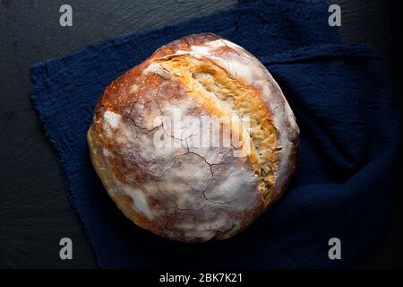 Dunkle Stimmung und Ton Home Kochen hausgemachte Bio rustikale Sauerteig Brot auf schwarzem Hintergrund mit Kopierraum Stockfoto