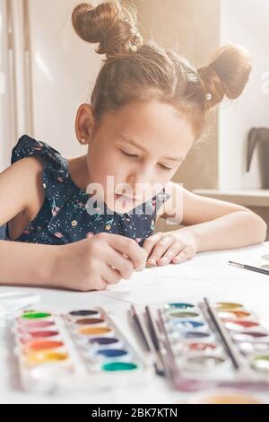 Nettes Mädchen zeichnet mit Bleistiften und Farben. Aktivitäten für Kinder unter Quarantäne gestellt. Vertikale Aufnahme Stockfoto