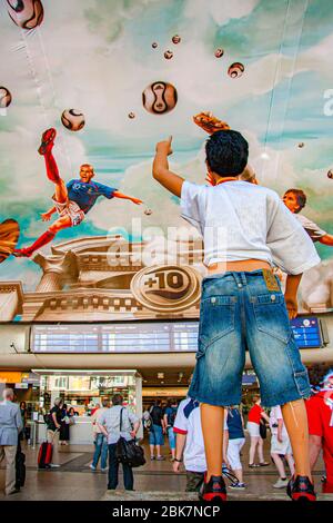 Deckenmalerei mit Fußballszenen am Hauptbahnhof, Köln, Deutschland. Während der FIFA Fußball-Weltmeisterschaft 2006. Auf einer Fläche von mehr als 800 Quadratmetern hat Adidas ein Fresko an der Decke des Kölner Hauptbahnhofs installieren lassen. In originalgetreuem antikem Look schweben Nationalspieler wie Michael Ballack, David Beckham, Zinédine Zidane und Juan Román Riquelme hoch über den Köpfen der Passanten Stockfoto