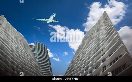 Kommerzielle Flugzeuge fliegen über hohe Wolkenkratzer in der Stadt. Ansicht von unten. Stockfoto