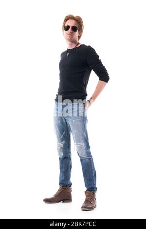 Attraktive junge rote Haare Mann Mode-Modell in zerrissenen Jeans und schwarzem Hemd trägt Sonnenbrille. Ganzkörper isoliert auf weißem Hintergrund. Stockfoto