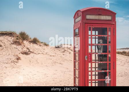 Eine alte britische rote Telefondose in den Sanddünen eines einsamen Strandes von Studland, in der Nähe von Sandbanks, Dorset, England, Großbritannien Stockfoto