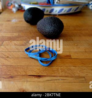 Reife Avocados auf einem Holzbrett mit blauen Gummibändern, die mit der Schrift "Produkt von Mexiko" geprägt sind; mexikanische Landwirtschaft, Export, Import. Stockfoto