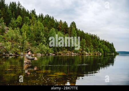 Fischer Mann mit Fliegenfischen in Berg Fluss Stockfoto